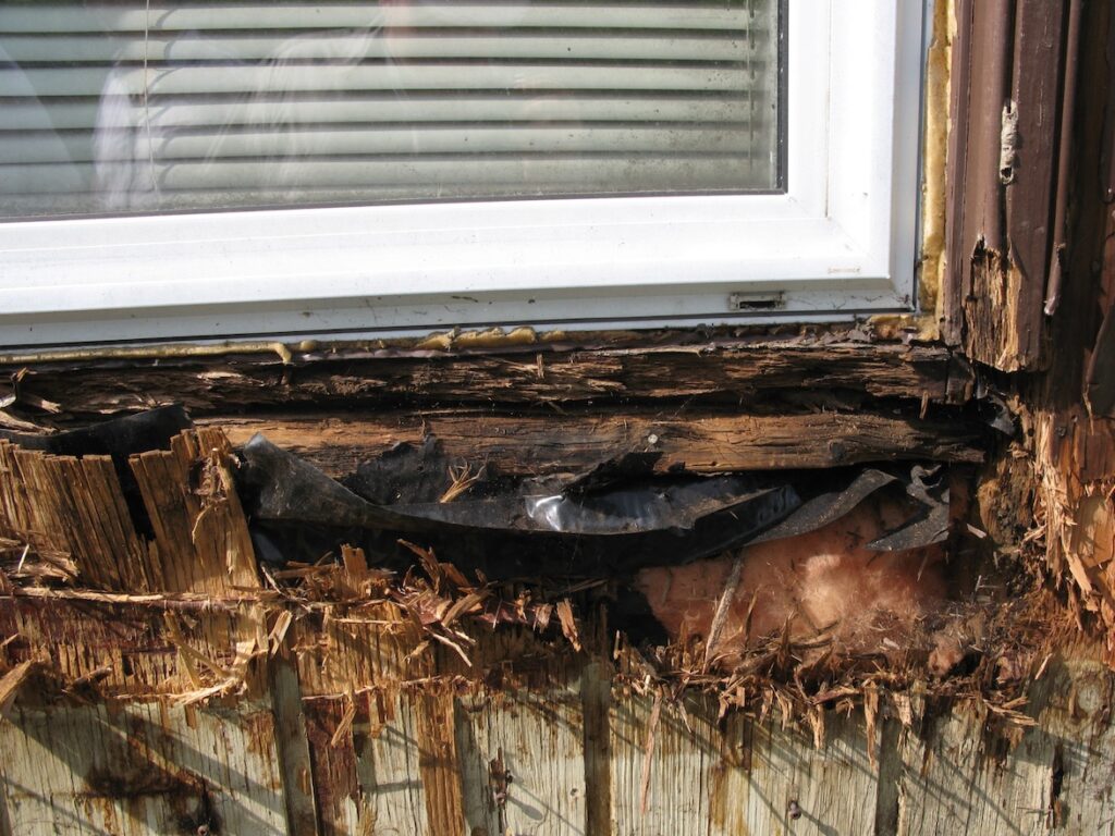 Deteriorated wood framing below a window, caused by ongoing leakage.
